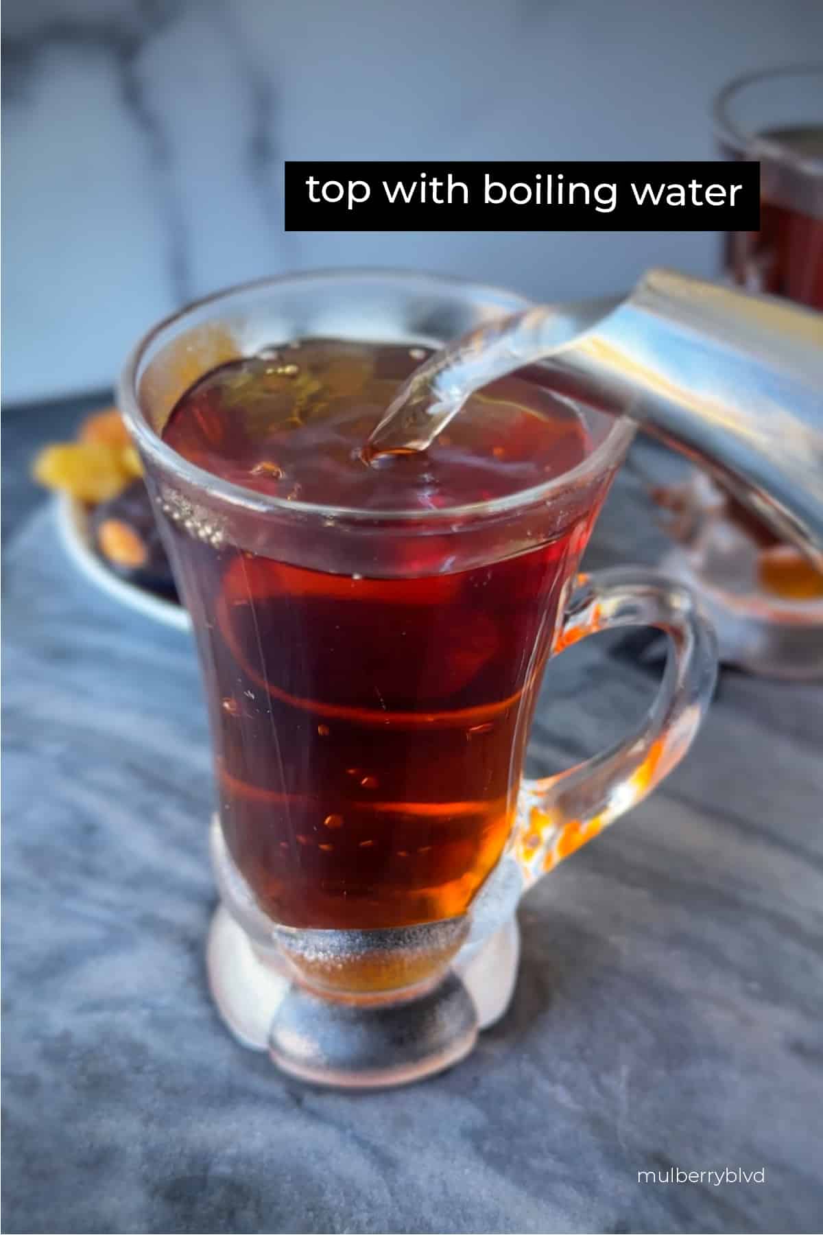 Hot water being added to tea in a glass cup