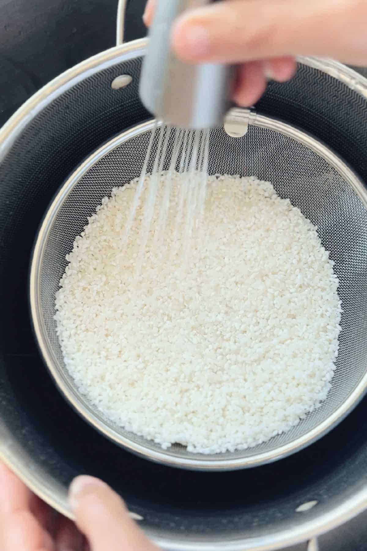 An image of the rice being washed in preparation to making a recipe for Tahdig Rice Balls with Shepherd's Pie Filling .
